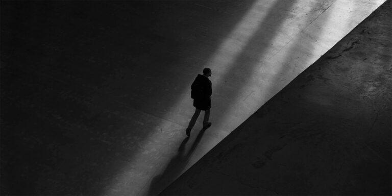Greyscale image of man walking on concrete
