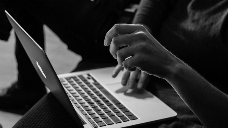 Greyscale image of two people on a laptop